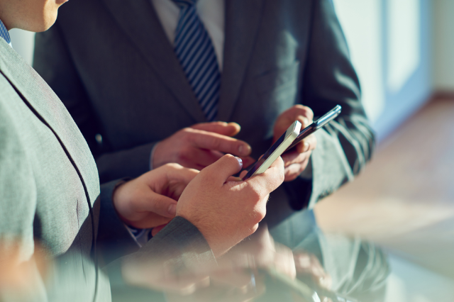 Kontakt Zwei Personen im Anzug tauschen Kontakt auf Smartphone aus